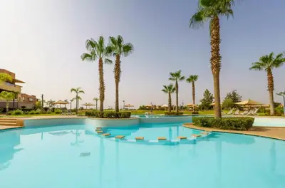 a large swimming pool with palm trees in a resort at Prestigia Golf View - Piscine & terrasse in Marrakech
