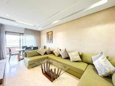 a living room with a green couch and a table at Prestigia Golf View - Piscine & terrasse in Marrakech