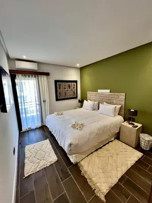 a bedroom with a large white bed and green walls at Appartement Luxe 2 Chambres Guéliz Centre Calme & Prestations Haut de Gamme in Marrakech