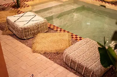 a swimming pool with two straw mats next to at Riad Amara Private pool breakfast in Marrakech