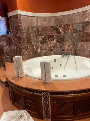 a bath tub in a bathroom with a stone wall at Villa Oum Palace in Marrakech