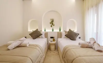 two beds in a room with white walls and windows at Appartement de luxe au Plaza, au coeur de Marrakech in Marrakech