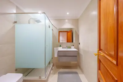 a bathroom with a sink and a glass shower at Appartement de luxe au Plaza, au coeur de Marrakech in Marrakech