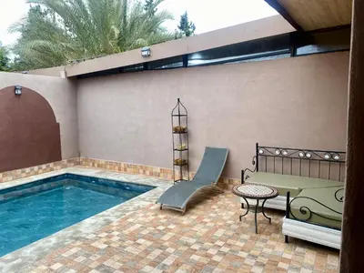 a swimming pool with a bench and a table next to it at Villa d'Exception avec Piscine Privée in Marrakech