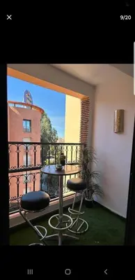a balcony with two stools and a table on a balcony at Le petit cocon in Marrakech