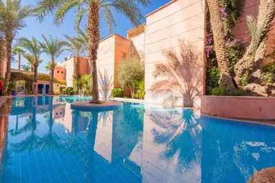a swimming pool with palm trees and a building at Riad Marrakech 88 Retro Chic 3 Rooms with Shared Pool in Marrakech