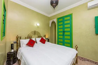 a bedroom with a bed with green doors and red pillows at Riad Marrakech 88 Retro Chic 3 Rooms with Shared Pool in Marrakech