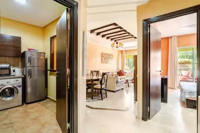 a kitchen and living room with a refrigerator and a table at Appartement marrakech garden in Marrakech