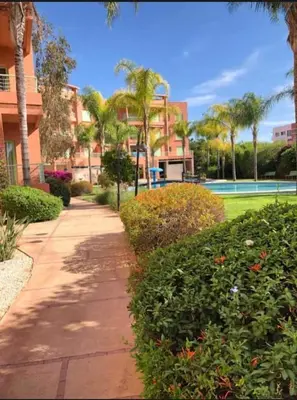 a sidewalk in front of a building with palm trees at Appartement marrakech garden in Marrakech