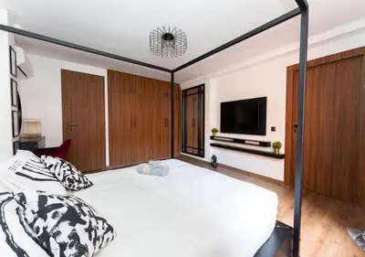 a bedroom with a large bed and a flat screen tv at Écrin Cosy au Cœur de Guéliz Emplacement Central in Marrakech