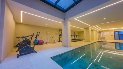 a gym with a swimming pool and exercise equipment at MOZAIC26 I Terrasse & Piscine couverte I Hivernage in Marrakech