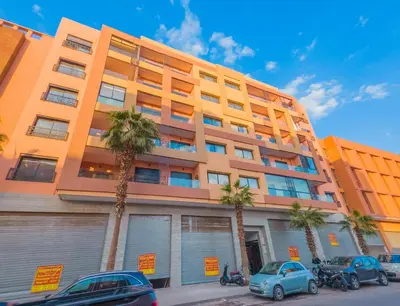 an orange building with palm trees in front of it at MOZAIC26 I Terrasse & Piscine couverte I Hivernage in Marrakech