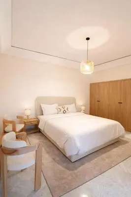 a bedroom with a large white bed and a chair at Luxury 2 Bedroom Apartment Pool & Garden Wifi in Marrakech