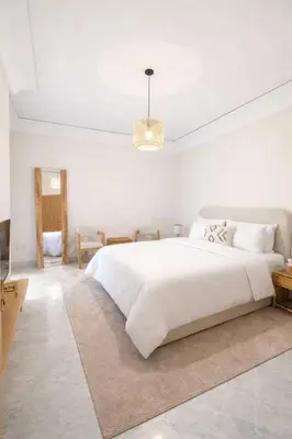 a white bedroom with a large bed and a chandelier at Luxury 2 Bedroom Apartment Pool & Garden Wifi in Marrakech
