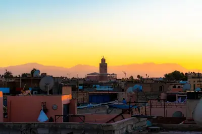 a city skyline with a clock tower at sunset at Riad Abrare-A in Marrakech