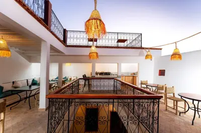 a room with a staircase and tables and chairs at Riad Abrare-A in Marrakech