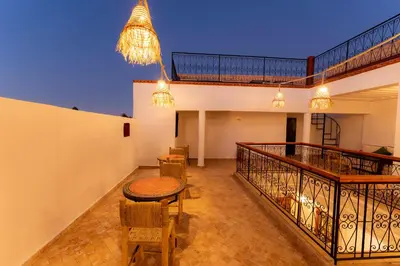 a balcony with a table and chairs and a chandelier at Riad Abrare-A in Marrakech