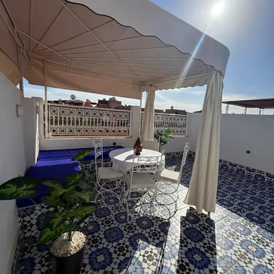 a patio with a table and chairs under an umbrella at White Riad Residence in Oulad Akkou