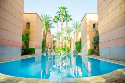 a swimming pool in a building with palm trees at White Riad Residence in Oulad Akkou