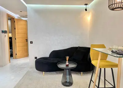 a living room with a black couch and a table at Verona Studio - 1 Bedroom Piscine & Rooftop in Marrakech