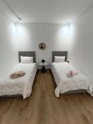 two beds in a room with white walls and wooden floors at Appartement a Menara garden in Marrakech