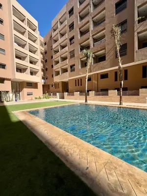 an empty swimming pool in front of a building at Appartement a Menara garden in Marrakech