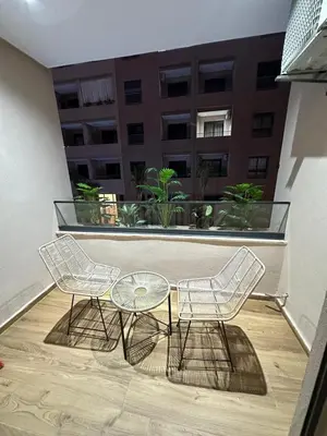 two chairs and a glass table on a balcony at Studio a Menara garden in Marrakech