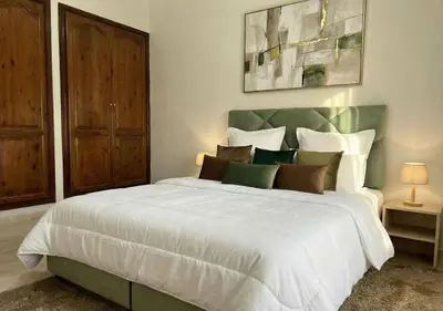 a bedroom with a large white bed with a green headboard at Appart Mobarak 5 in Marrakech