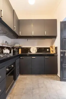 a kitchen with black cabinets and a counter top at Maison Meurisse Tlata private and Daily Breakfast in Marrakech