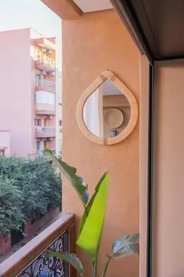 a mirror on a wall with a plant on a balcony at Sublime appartement 2 chambres en plein centre entre Gueliz et hivernage avec piscine in Marrakech