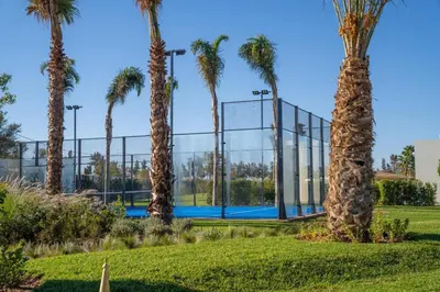a tennis court between palm trees in a park at THE ESTATE - Marrakech in Marrakech