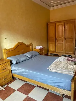 a bedroom with a bed with a wooden headboard and wooden cabinets at Appartement meublé calme près de l'aéroport menara in Marrakech