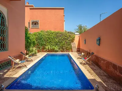 a swimming pool with two chairs and a building at Hôtel Boutique RAM SPA in Marrakech