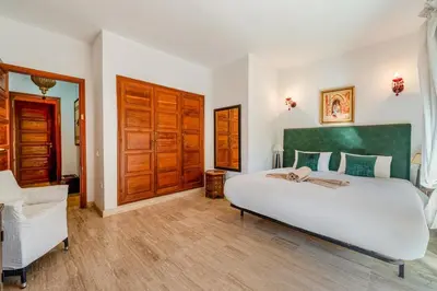 a bedroom with a large white bed and wooden doors at Bright & Cozy Appt with Exclusive Private terrace in Marrakech