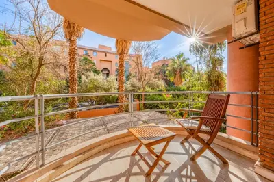 a patio with a chair and an umbrella on a balcony at Bright & Cozy Appt with Exclusive Private terrace in Marrakech