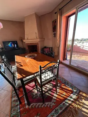 a table and chairs in a living room with a fireplace at Appartement avec piscine Vue colline à Gueliz in Marrakech