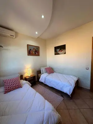 a room with two beds and a table with a lamp at Appartement avec piscine Vue colline à Gueliz in Marrakech