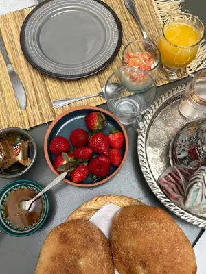 a table with plates of food and a bowl of strawberries at Riad melqa piscine privée - Medina Marrakech in Marrakech