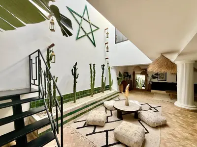 a living room with a table and stools at Maison Meurisse Sta'a private pool breakfast in Marrakech