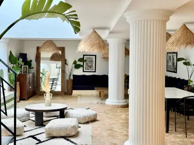 a living room with white columns and a table at Maison Meurisse Sta'a private pool breakfast in Marrakech