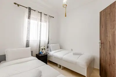 two beds in a room with white walls at Spacious Can 2025 Iptv Guéliz 7 min away in Marrakech