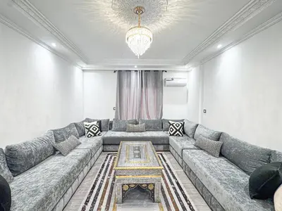 a living room with a large couch and a chandelier at Urban Cocoon Quiet and modern in Marrakech