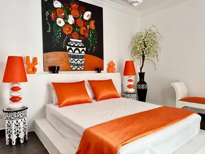 a bedroom with a bed with orange pillows and a painting at Riad Florival breakfast private kasbah in Marrakech