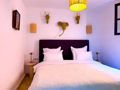 a bedroom with a white bed with white pillows and antlers at Maison Meurisse KHAMSaPrivate pool and breakfast in Marrakech