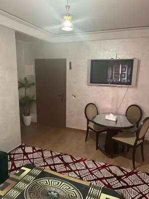 a living room with a table and a tv on the wall at Appt á louer TF2 in Marrakech