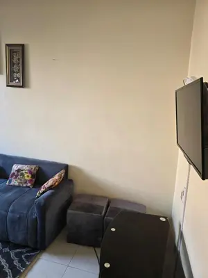 a living room with a blue couch and a flat screen tv at Beautiful comfortable apartment in a secure residence in Marrakech