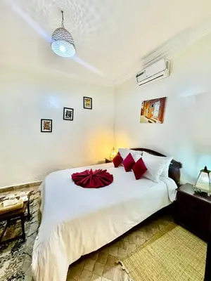 a bedroom with a large white bed with red pillows at Riad Iklil hcekarram in Marrakech