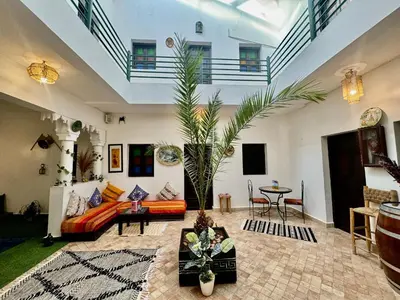 a living room with a couch and a palm tree at Riad Iklil hcekarram in Marrakech