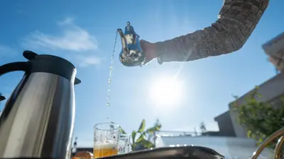 a person is pouring a drink into a glass at Riad Dreams Med in Marrakech