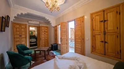 a bedroom with a bed and a chair and a chandelier at Riad Dreams Med in Marrakech